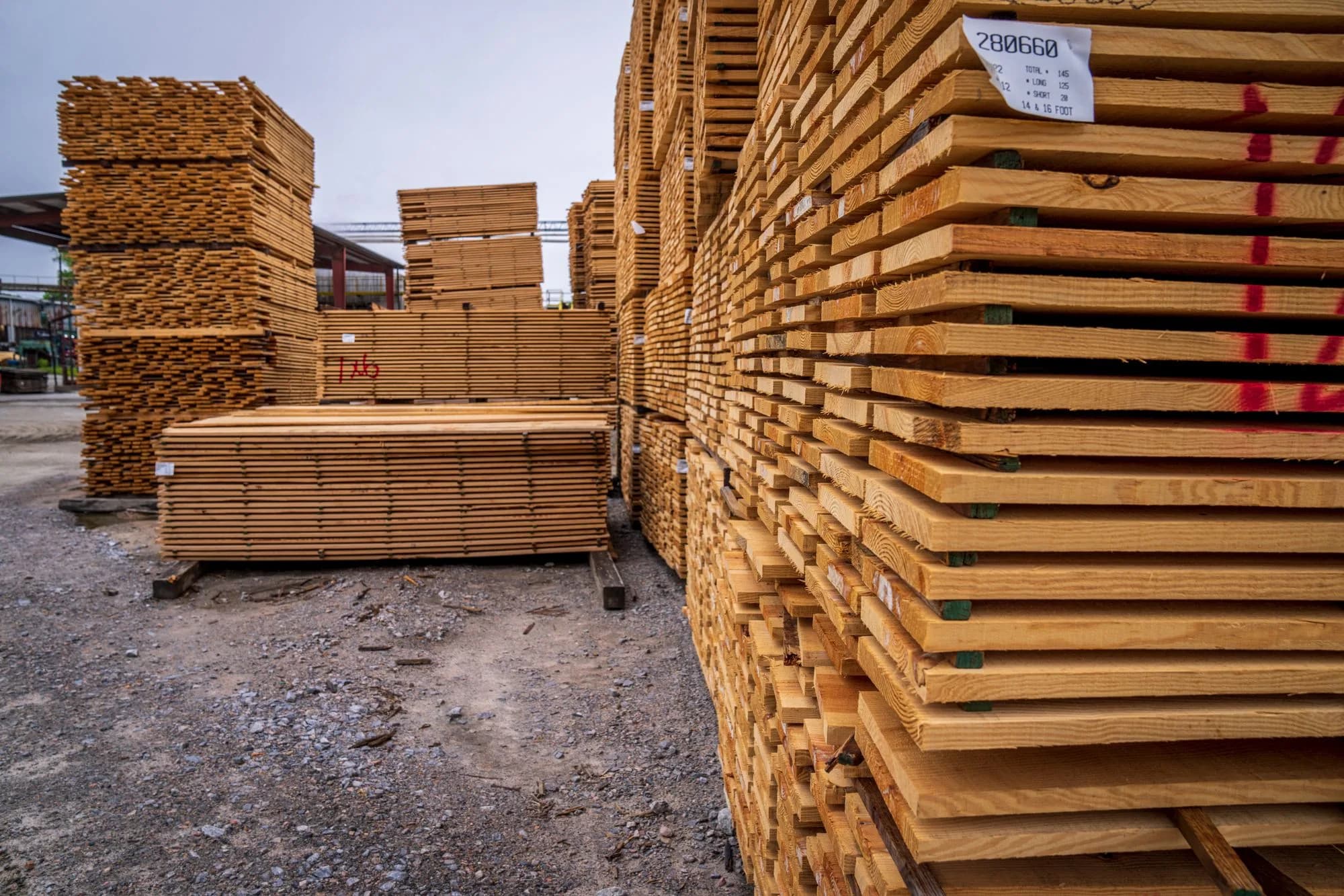 Tall stacks of pressure-treated lumber planks stored outdoors at a lumber yard