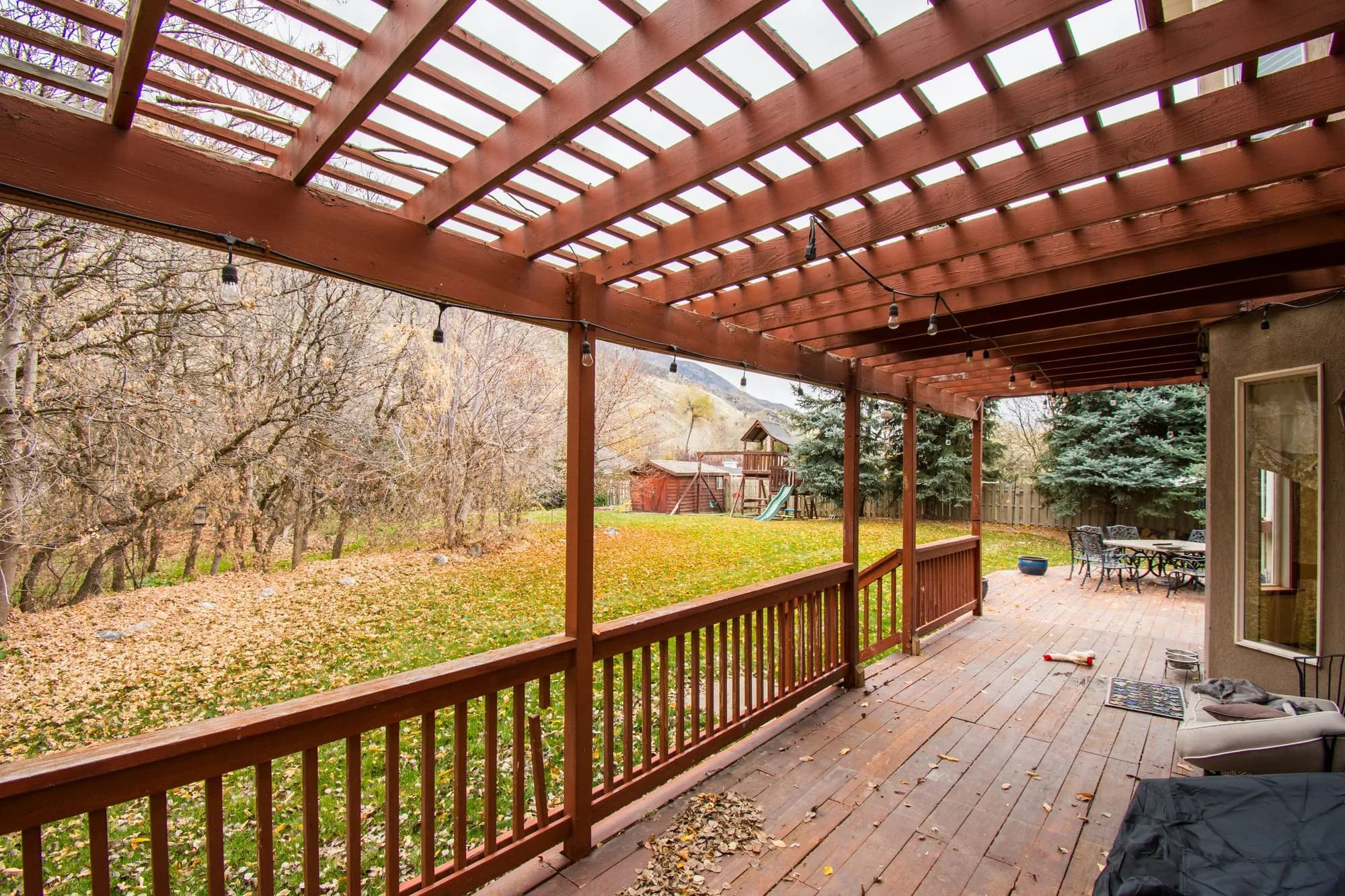 A wooden deck scattered with autumn leaves