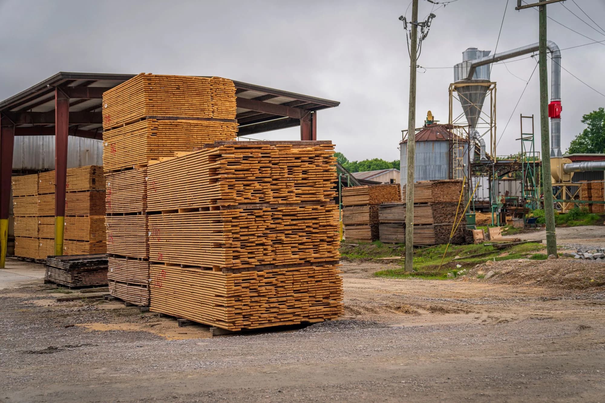 Large stacks of pressure-treated lumber piled outdoors at a sawmill and lumber yard