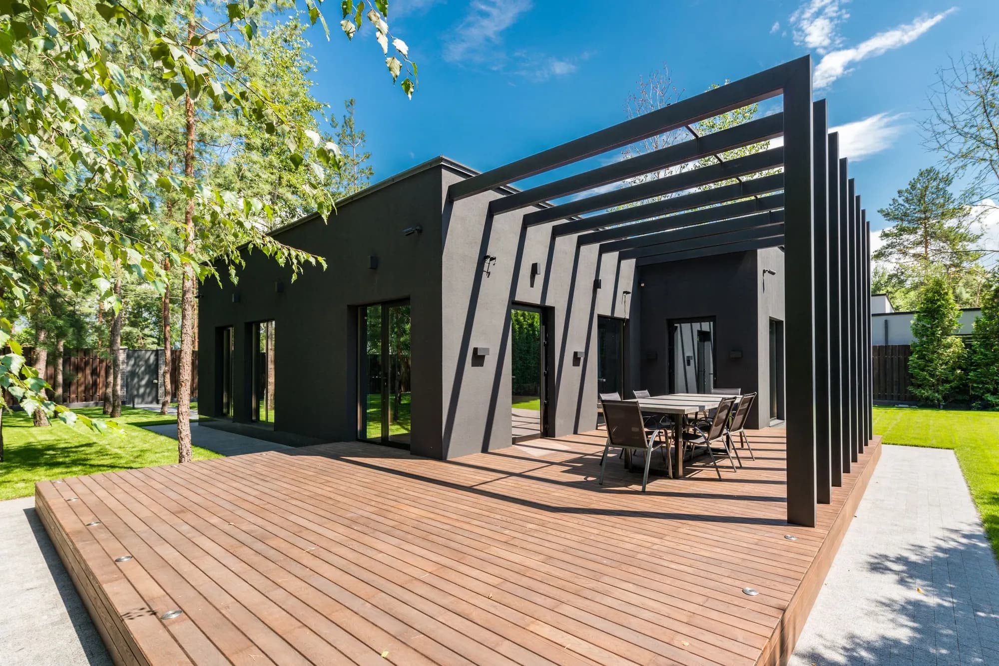 A finished cedar deck with a pergola behind a modern charcoal-clad house